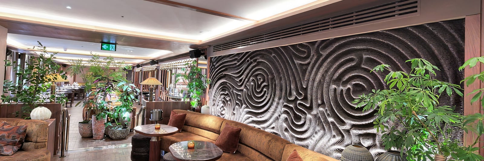 Lounge seating beneath the carved wave wall, with the planted corner beyond